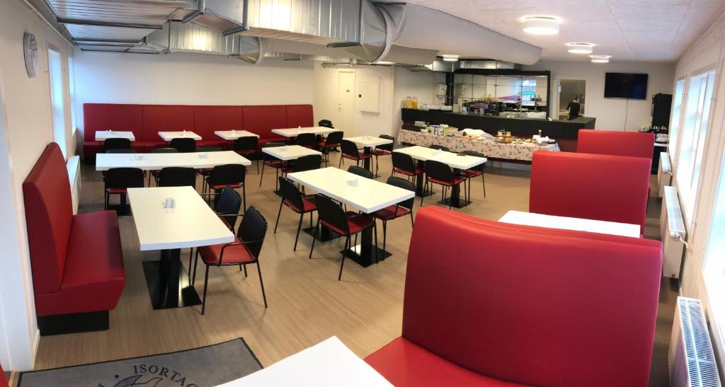 a restaurant with tables and red chairs and a counter at Hotel Nuka in Ilulissat