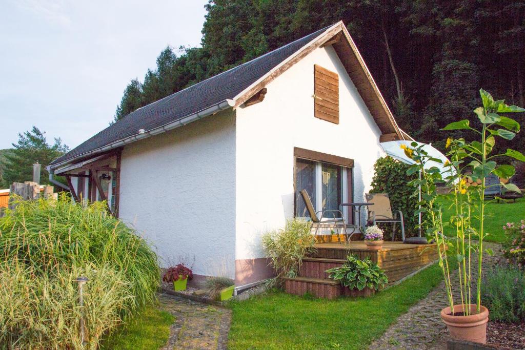 a small white house with a porch in a yard at Kleines Ferienhaus zu Füßen des Rennsteigs in Ruhla