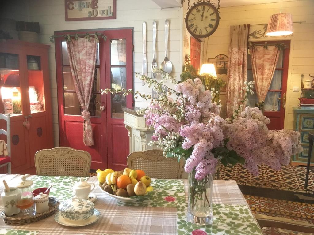 einen Tisch mit einer Vase aus Blumen und Obst darauf in der Unterkunft Ô fil de L'ô in Clairac