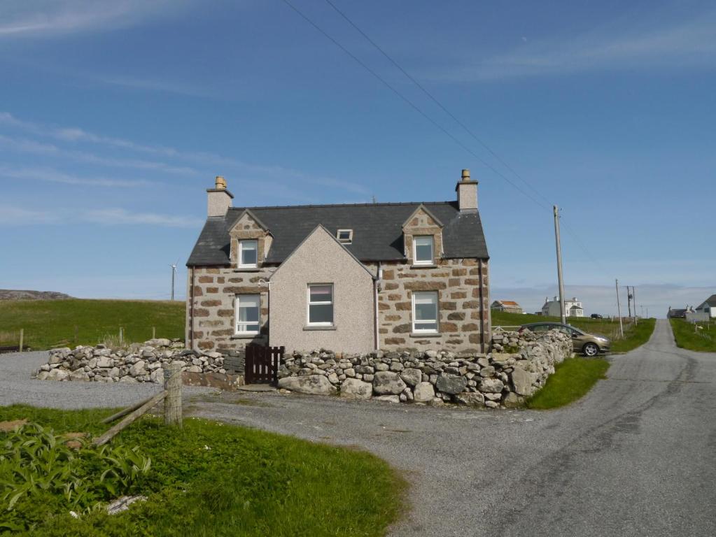 une maison en pierre sur le côté d'une route dans l'établissement Sineag's Cottage, à Pollachar