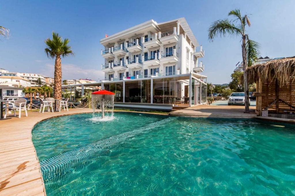 a pool with a fountain in front of a hotel at Poda Boutique Hotel Ksamil in Ksamil