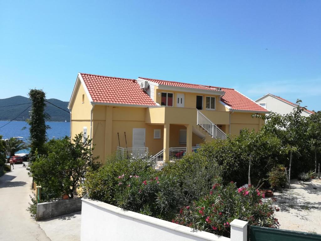 維甘的住宿－Apartmani Nedjeljka，黄色的房屋,有红色的屋顶