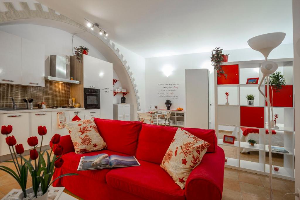a red couch in a room with a kitchen at Sicily Mon Amour Ortigia in Siracusa