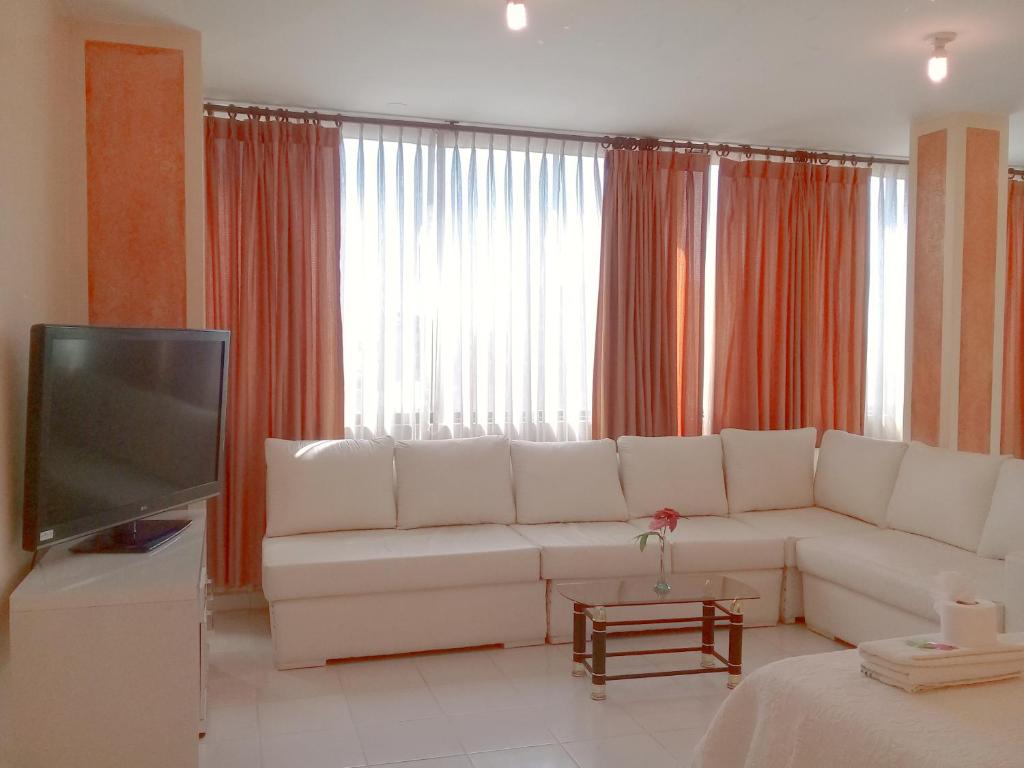 a living room with a white couch and a television at HOTEL MAISON FIORI (Centro) in Cochabamba