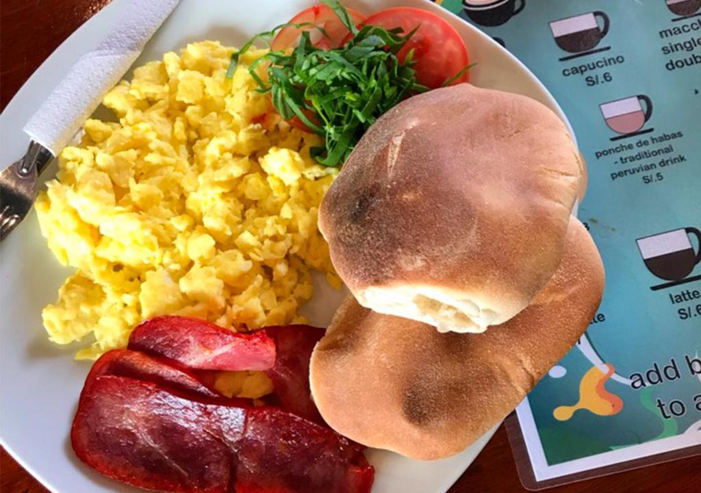a plate of scrambled eggs and bacon and a sandwich at Loki Cusco in Cusco