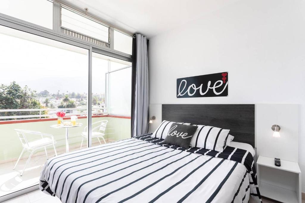 プエルト・デ・ラ・クルスにあるEdificio Las Marañuelas, Puerto La Cruz, Islas Canarias Tenerifeのベッドルーム1室(ベッド1台、上にラブサイン付)