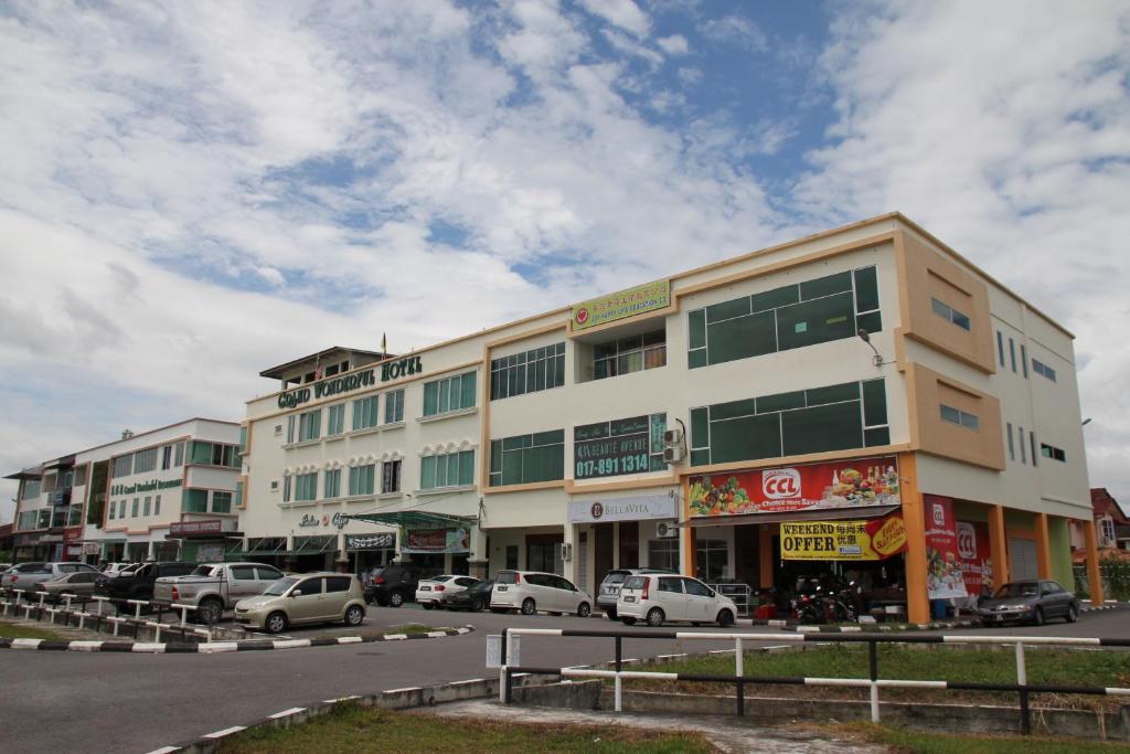 un grand bâtiment avec des voitures garées dans un parking dans l'établissement Grand Wonderful Hotel, à Sibu