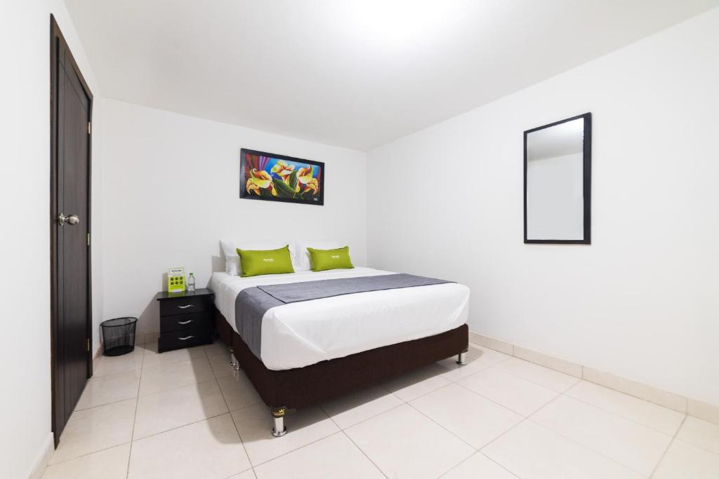 a white bedroom with a bed with green pillows at Ayenda 1045 Boutique Aeropuerto in Bogotá