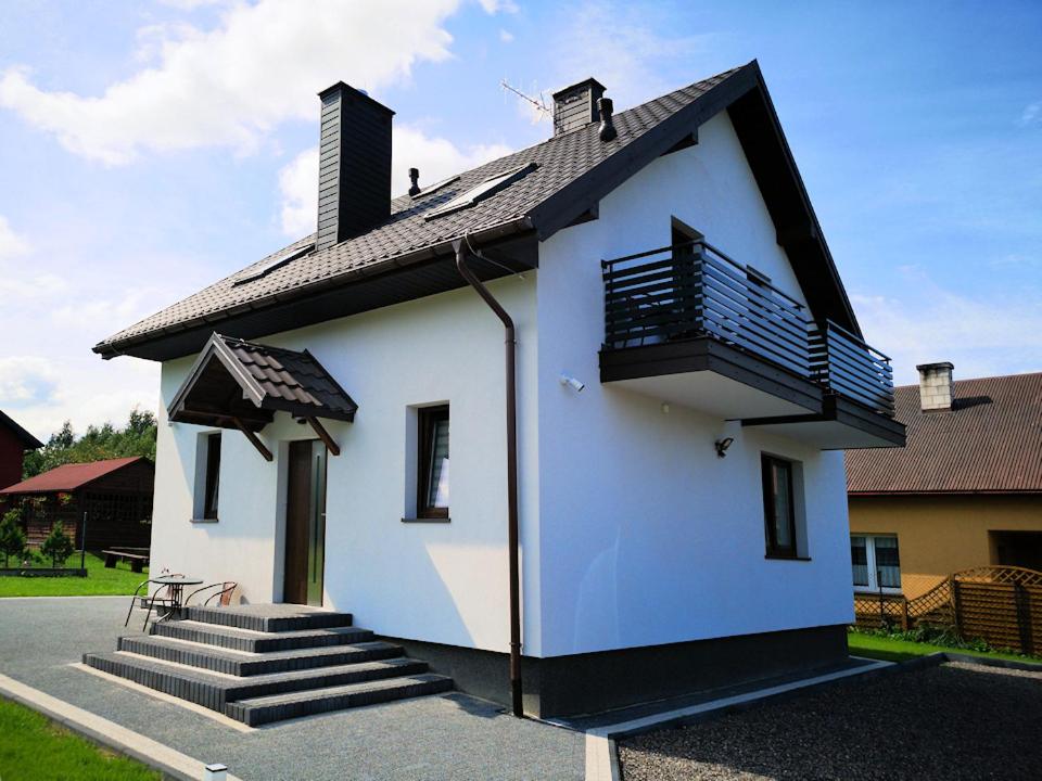 シフィエンタ・カタジナにあるAgroturystyka Katarzynaの小さな白い家で、バルコニーと階段が付いています。