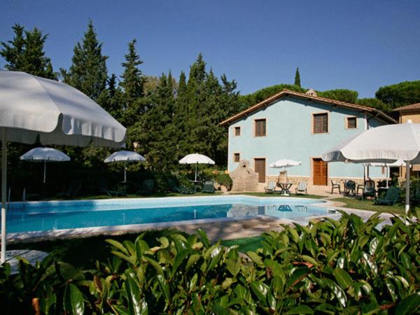 ein Pool mit Sonnenschirmen vor einem Haus in der Unterkunft Rifugio Da Giulia in Paganico