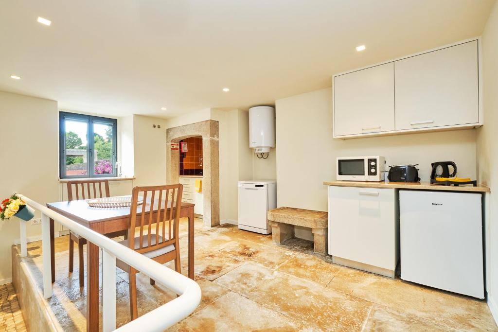 a kitchen with white cabinets and a table with a tableablish at Sintra Bliss A Part in Sintra