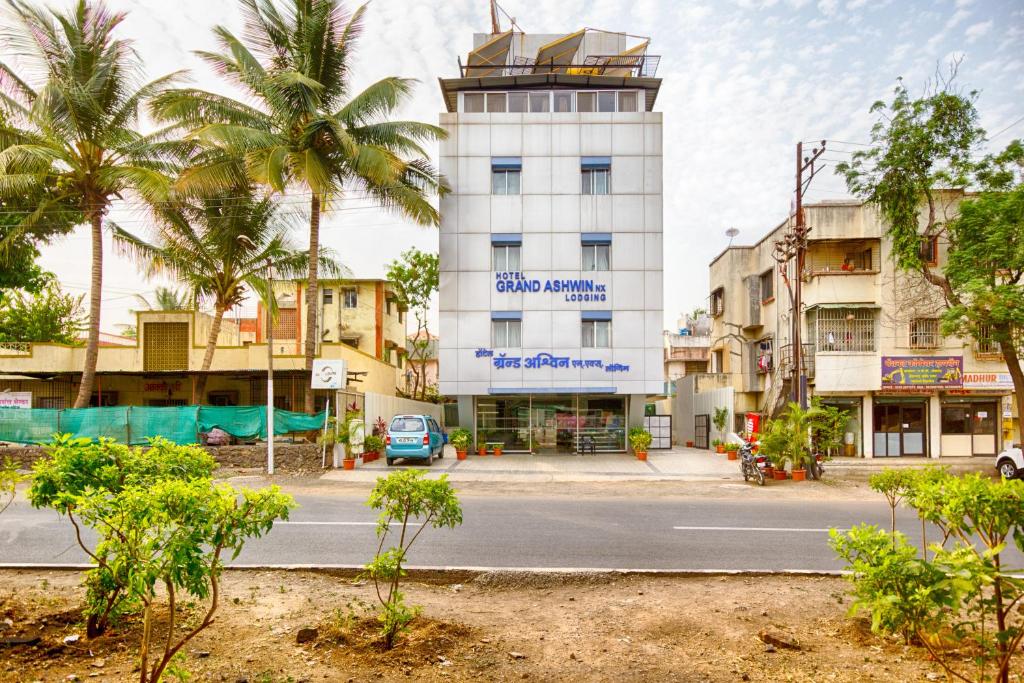 ein Gebäude in einer Straße mit Palmen in der Unterkunft Hotel Grand Ashwin in Nashik