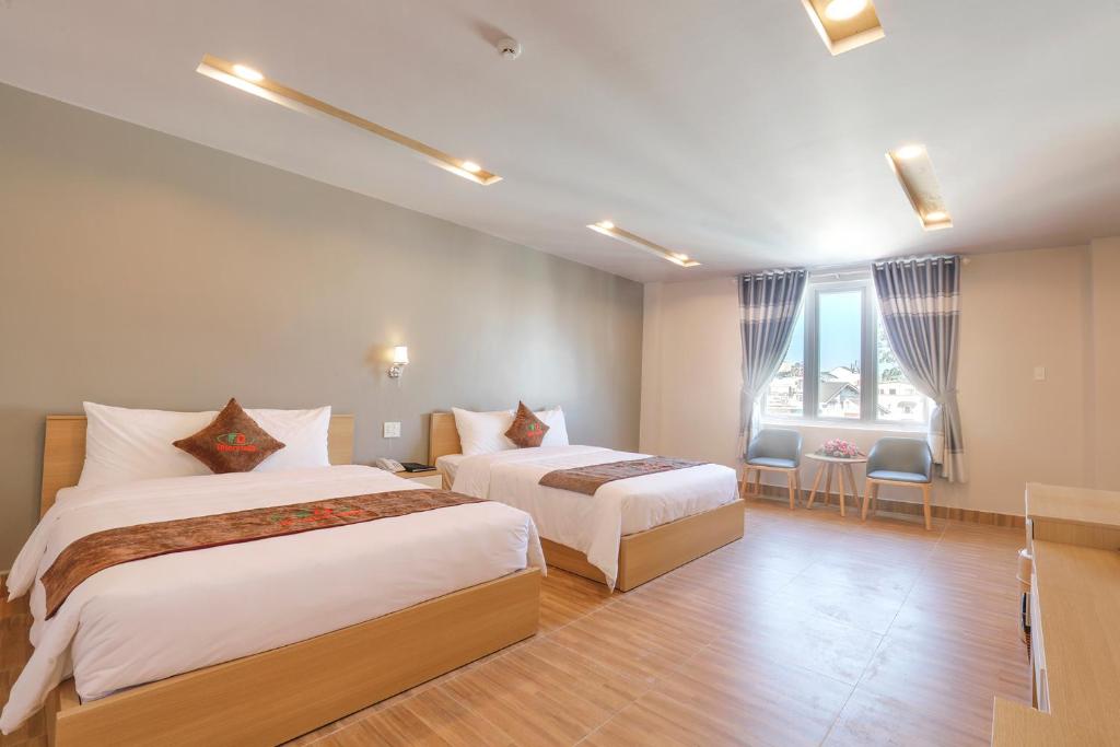 a hotel room with two beds and a window at Interstella Hotel in Da Lat