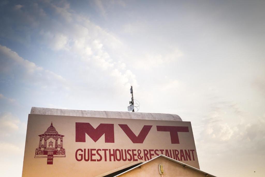 a sign on top of a building with the sky in the background at MVT Guesthouse & Restaurant in Vrindāvan