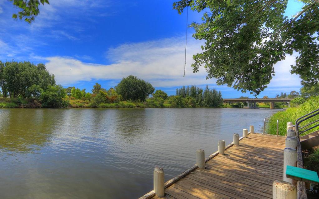 a dock on a river with a bridge in the background at NRMA Bairnsdale Riverside Holiday Park in Bairnsdale