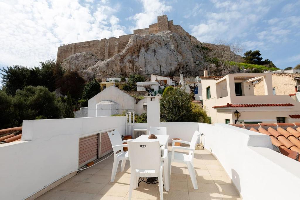 a balcony with white chairs and a view of a mountain at In the shadow of Acropolis in Athens