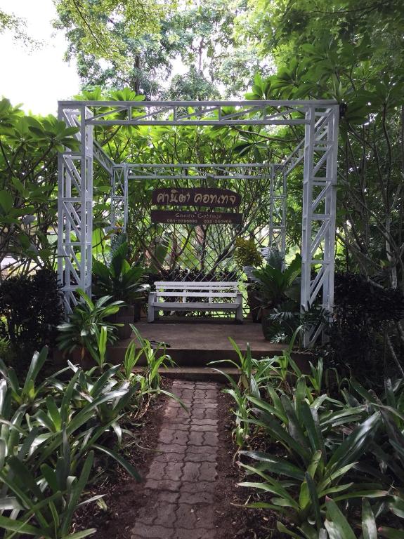 a white gate with a bench in a garden at Sanita Cottage in Chom Bung