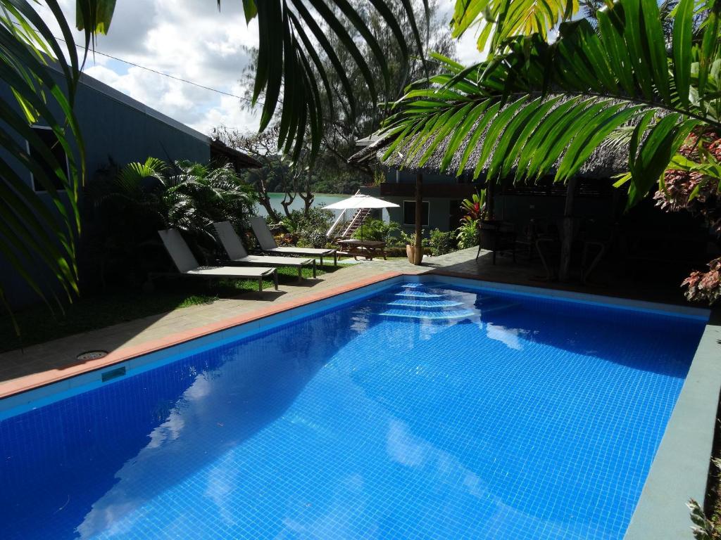 a blue swimming pool with chairs and palm trees at The Hub Vanuatu in Port Vila