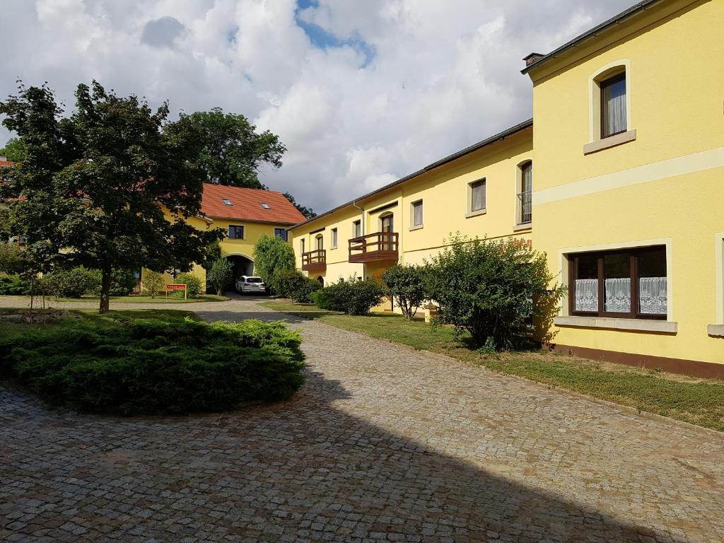eine Kopfsteinpflasterstraße vor einem gelben Gebäude in der Unterkunft Bärchenhof in Priestewitz