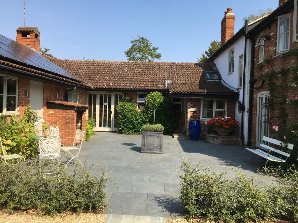 a courtyard of a house with a bench in front of it at Snipe Vineyard Cottage in Woodbridge