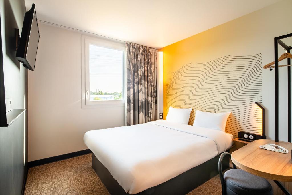a hotel room with a large bed and a table at B&B HOTEL Igny Palaiseau in Igny