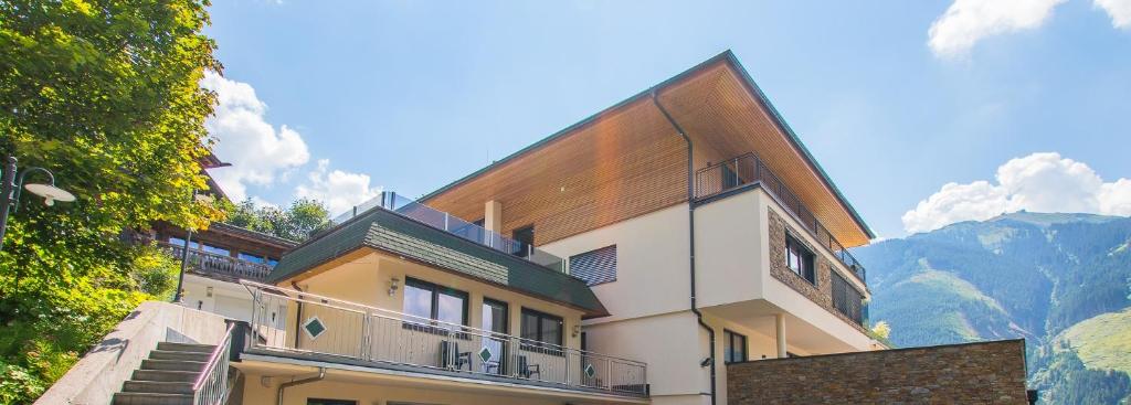 ein Gebäude mit einem Balkon mit Bergblick im Hintergrund in der Unterkunft Appartment Hotel Mitterer in Saalbach-Hinterglemm