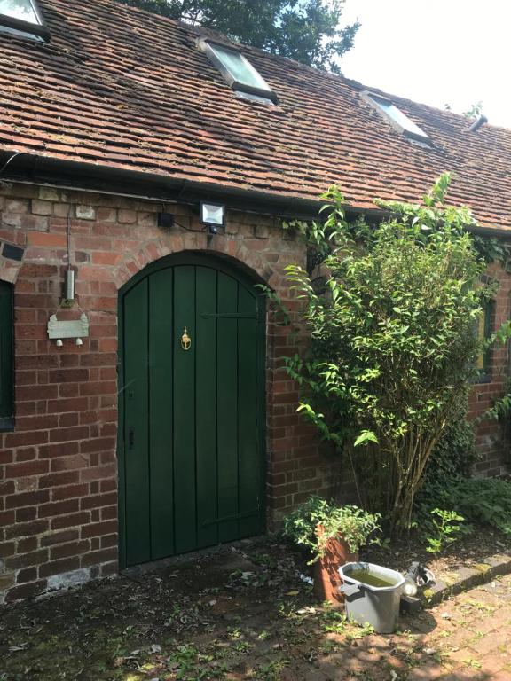 a green garage door on a brick house at Pet Friendly Dairy Cottage in Solihull