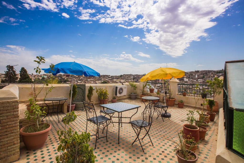 un patio avec des tables, des chaises et des parasols sur le toit dans l'établissement Riad Zina Fes - Elegance in the Heart of Fes, à Fès