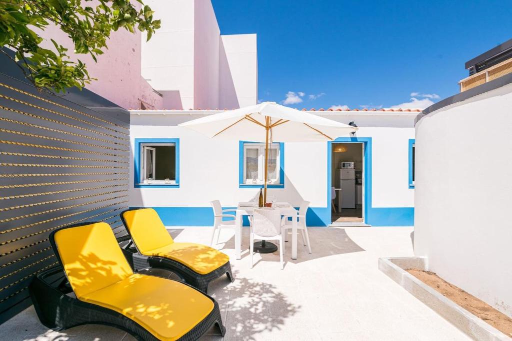 eine Terrasse mit Stühlen, einem Sonnenschirm und einem Tisch in der Unterkunft LovelyStay - Sweet Escape II - Backyard in Quarteira