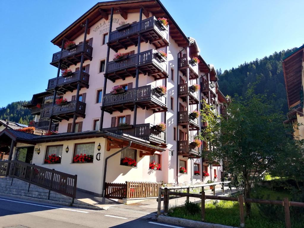 un alto edificio con balconi e fiori di Hotel Villa Emma a Madonna di Campiglio