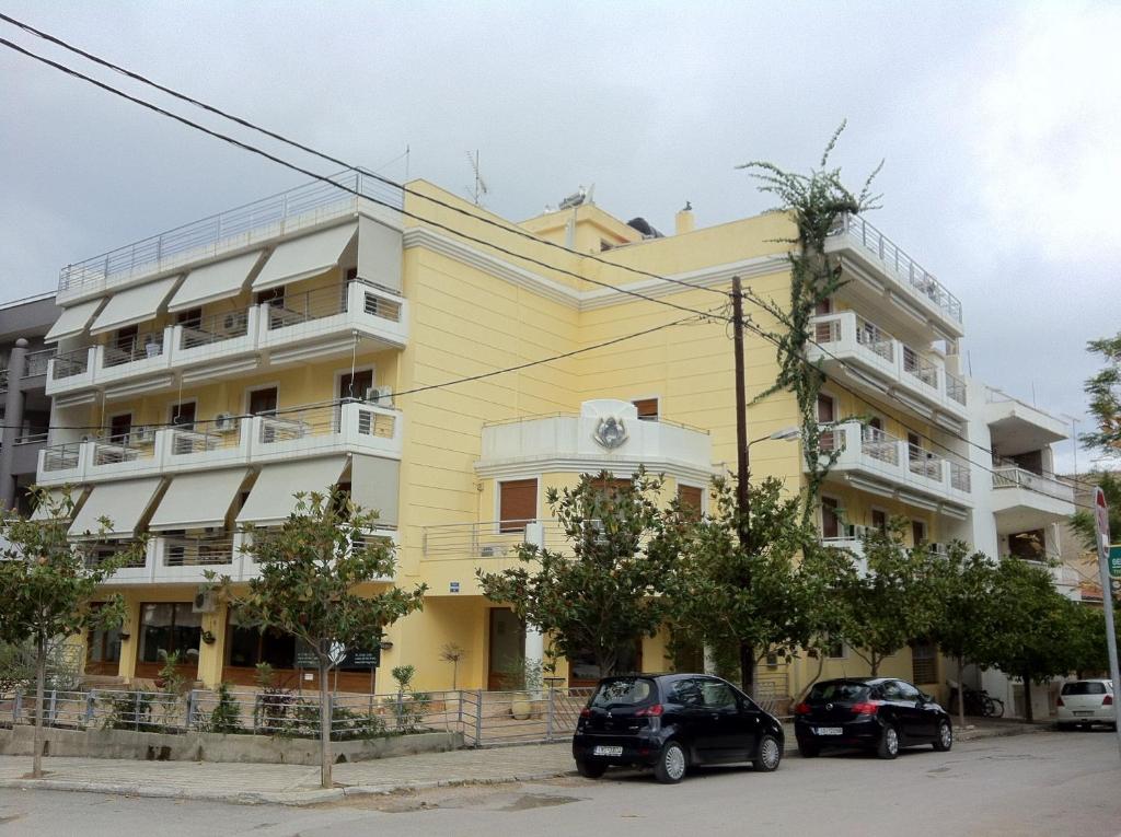 un edificio amarillo con coches estacionados frente a él en Hotel Magnolia, en Loutra Edipsou
