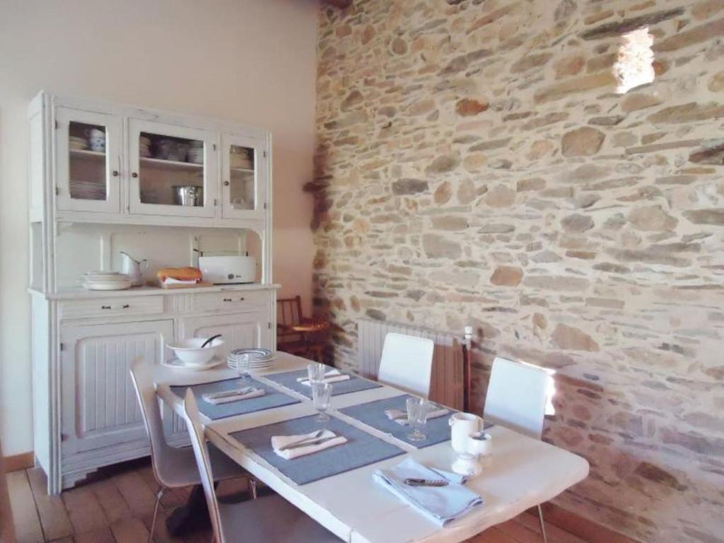 a dining room with a table and a stone wall at La Merise Gite in Villefranche-dʼAlbigeois