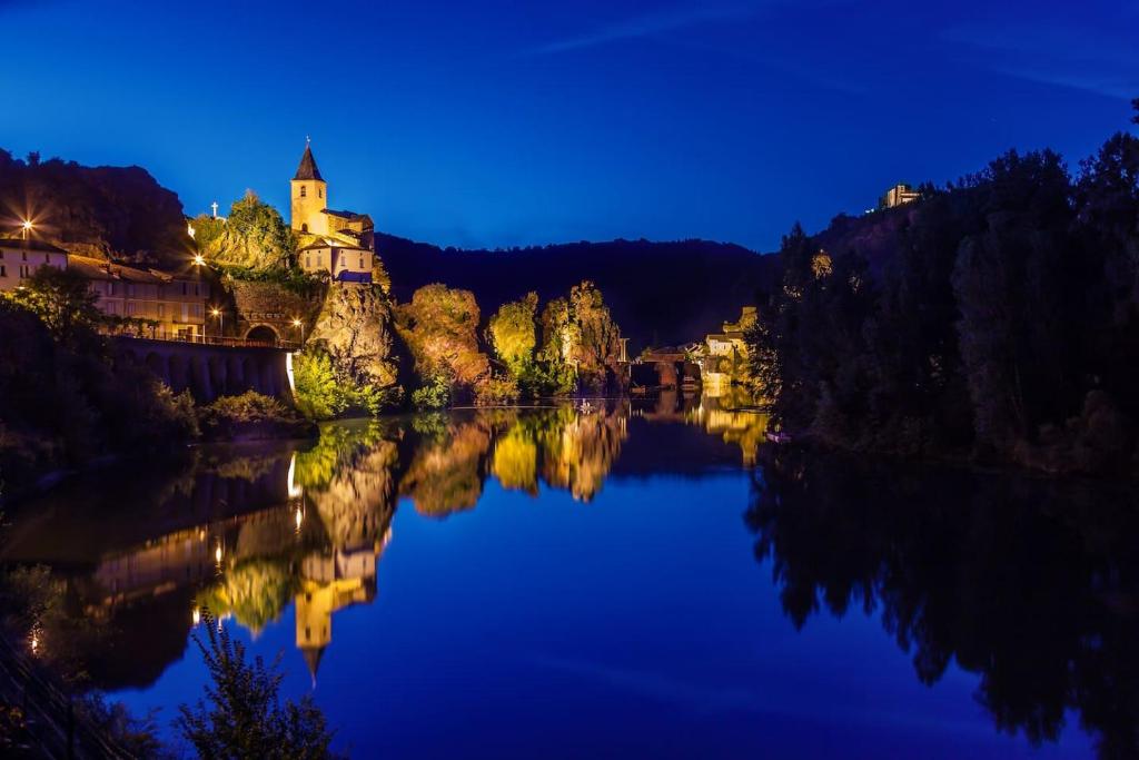 a castle on a hill next to a lake at night at La Merise Gite in Villefranche-dʼAlbigeois