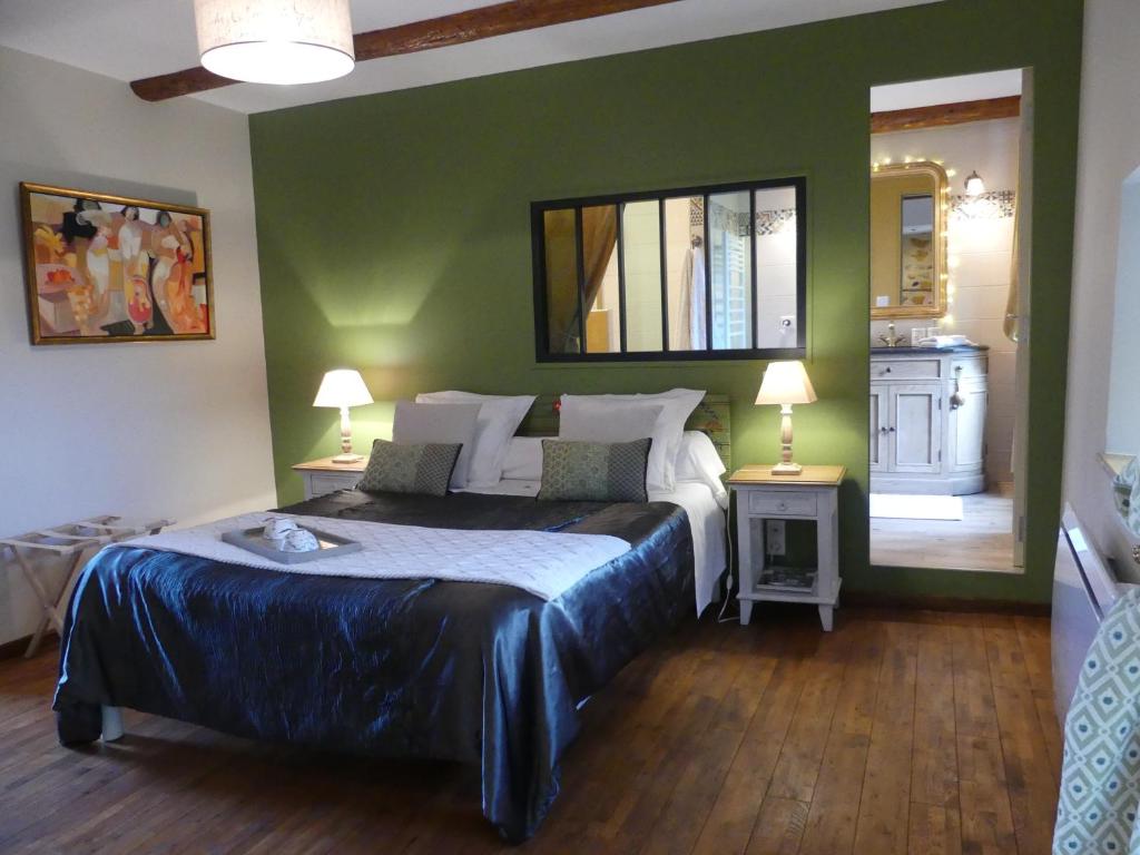 ein Schlafzimmer mit einem Bett und einer grünen Wand in der Unterkunft la maison de roussi in Nonette