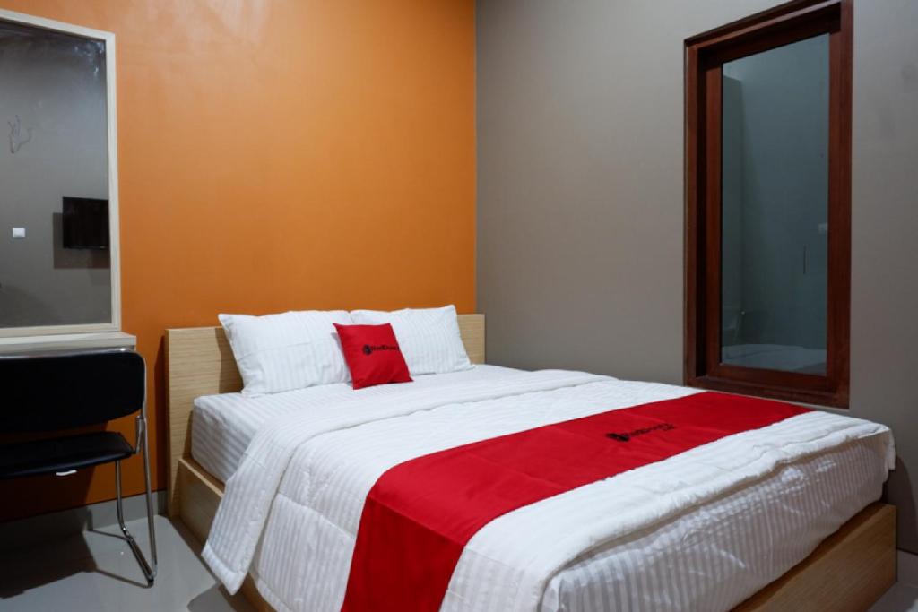 RedDoorz Syariah near Stasiun Tegal في تيغال: غرفة نوم بسرير كبير مع بطانية حمراء