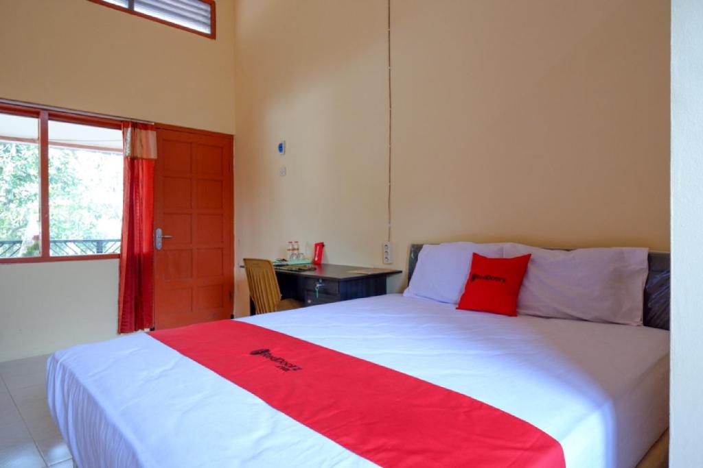 um quarto com uma cama grande e um cobertor vermelho em RedDoorz Syariah near Alun Alun Purwokerto em Purwokerto