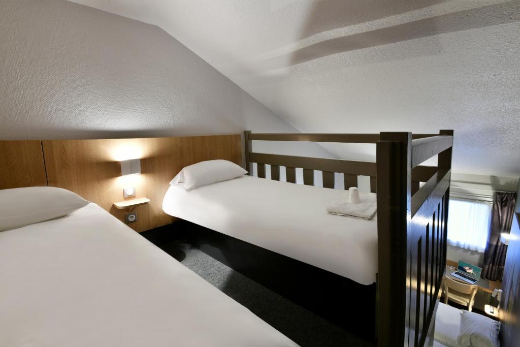 two beds in a small room with white sheets at B&B HOTEL La Rochelle Angoulins in Angoulins-sur-Mer