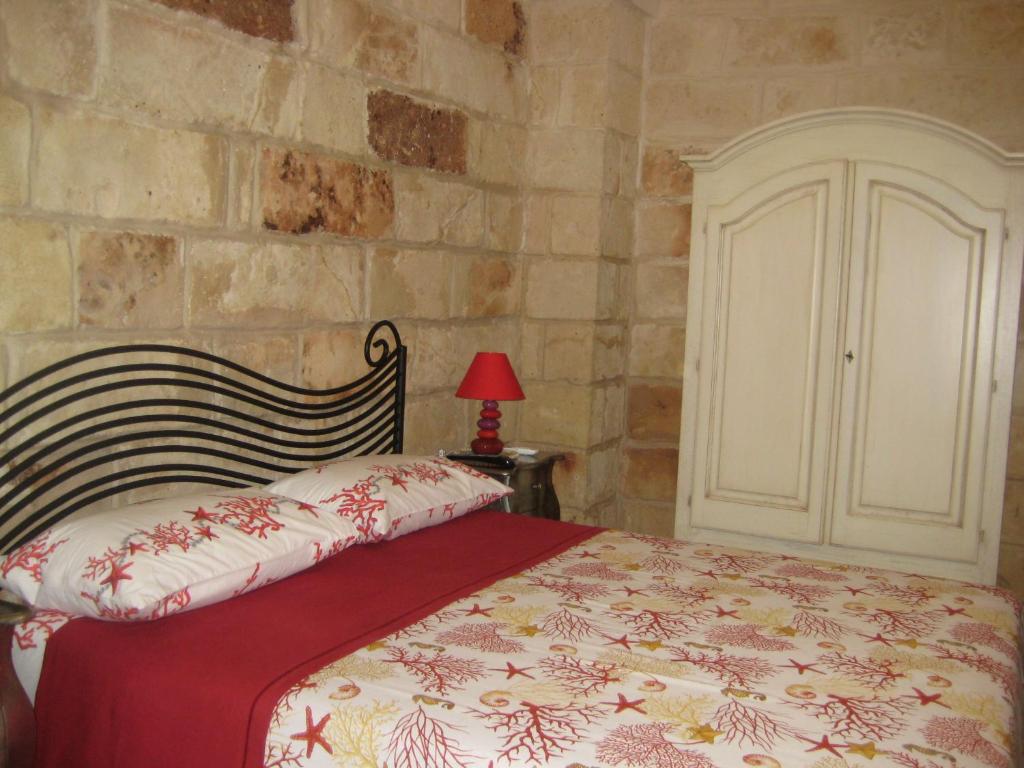 a bedroom with a bed and a stone wall at Grekal Bed Salento in Porto Cesareo