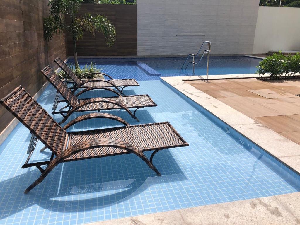 uma piscina com quatro cadeiras e uma piscina em Veranno Di Porto-50mts Piscinas Naturais em Porto de Galinhas