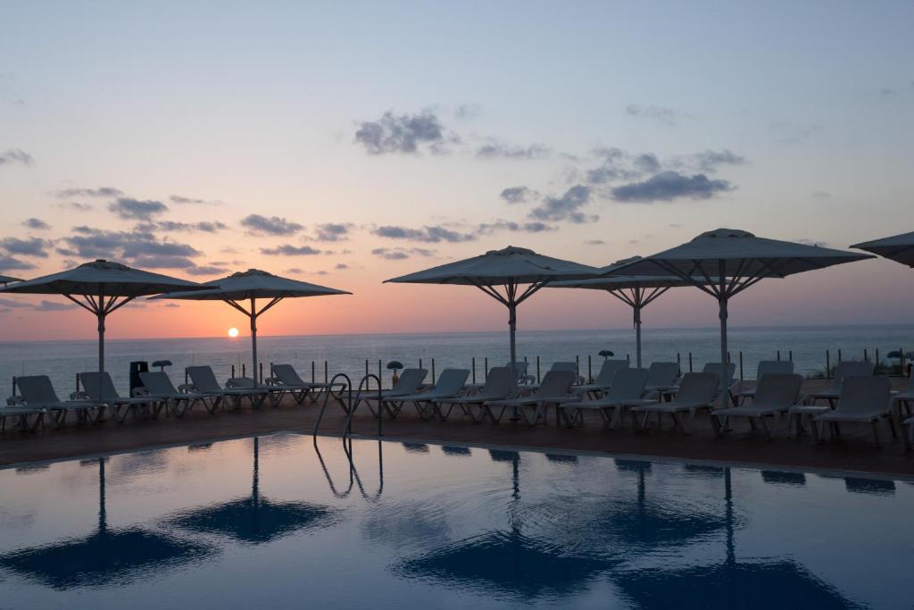 a pool with chairs and umbrellas on a beach at Island Luxurious Suites Hotel and Spa- By Saida Hotels in Netanya