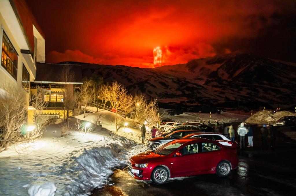 un'auto rossa parcheggiata in un parcheggio con un incendio sullo sfondo di Corsaro Etna Hotel&SPA a Nicolosi