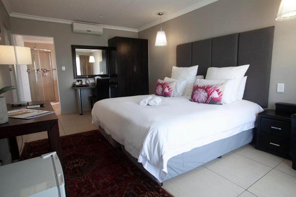 Schlafzimmer mit einem großen weißen Bett und einem Schreibtisch in der Unterkunft Ruslamere Hotel and Conference Centre in Durbanville