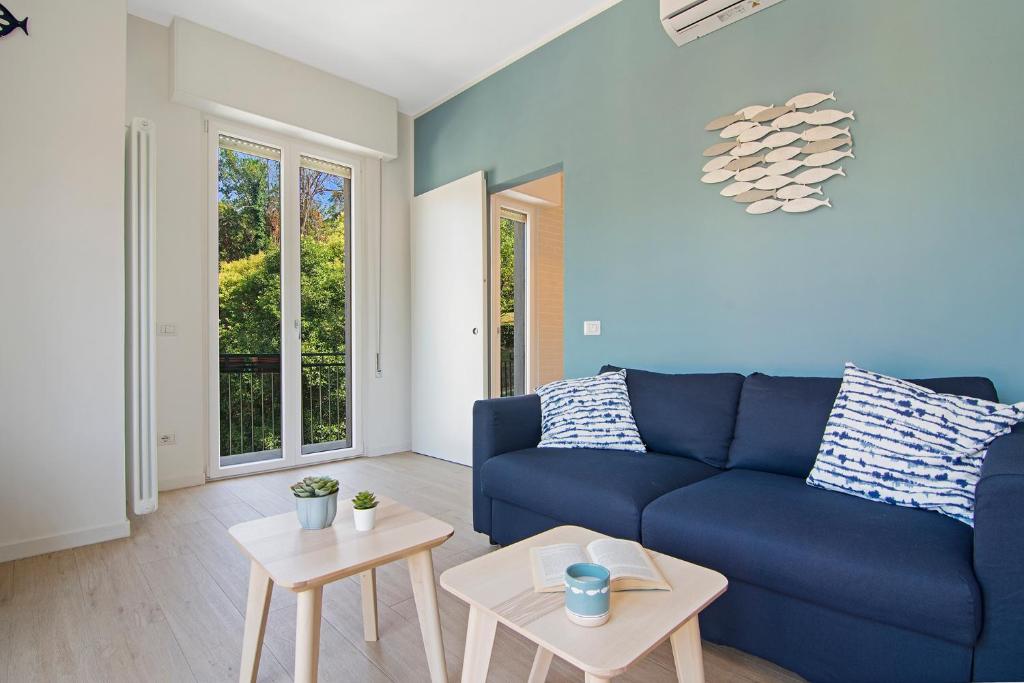 een woonkamer met een blauwe bank en 2 tafels bij Casa Babette by PortofinoHomes in Rapallo
