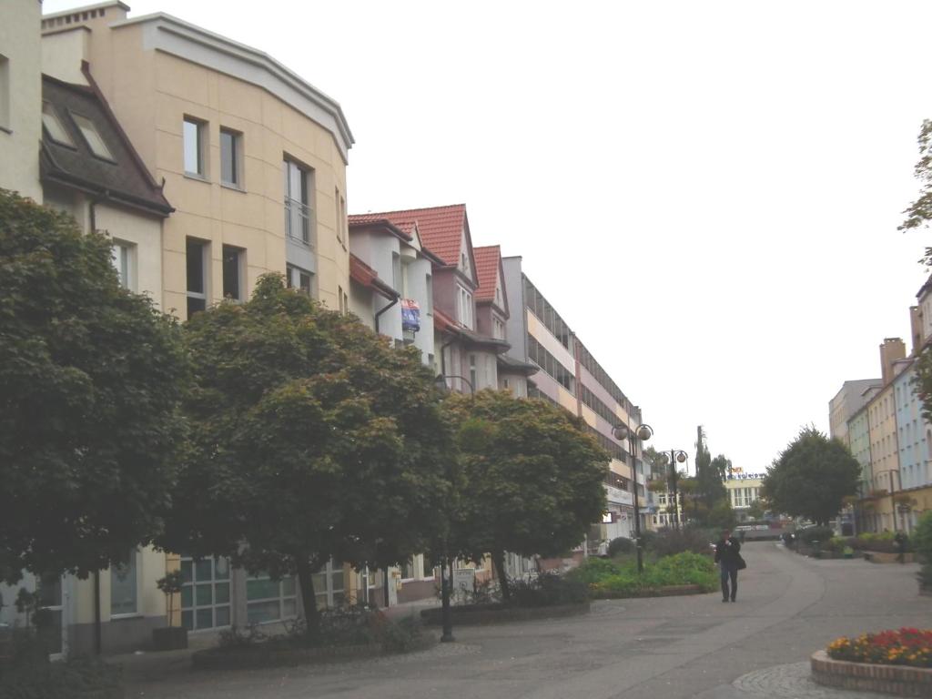 une personne marchant dans une rue à côté des bâtiments dans l'établissement 5A Hotel Services, à Koszalin