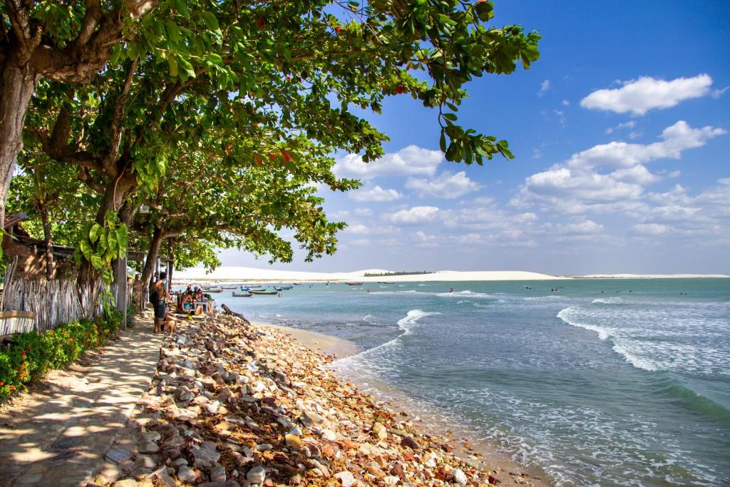 una playa con árboles y el océano en un día soleado en Pousada Ponta Da Pedra, en Jericoacoara