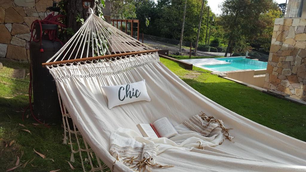 una hamaca con libros y libros junto a una piscina en Cabañas Chic Boutique en Sierra de los Padres