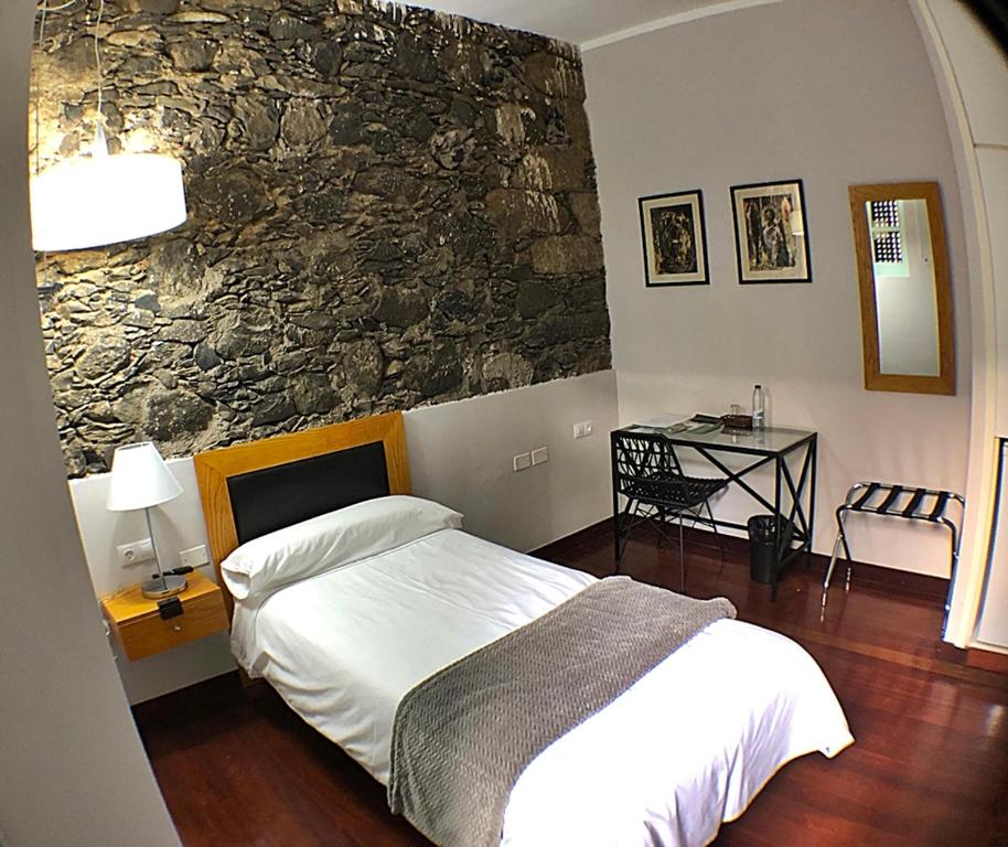 a bedroom with a bed and a stone wall at Hotel Rural Triana in Vallehermoso