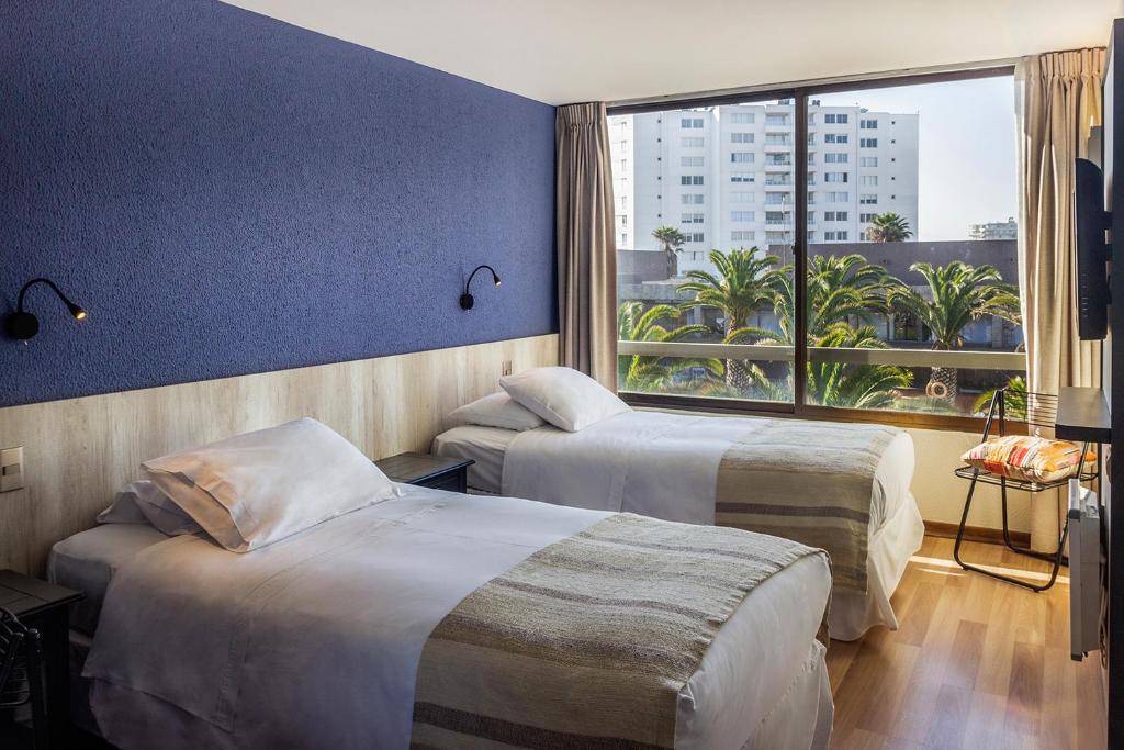 a hotel room with two beds and a large window at Hotel Club La Serena in La Serena