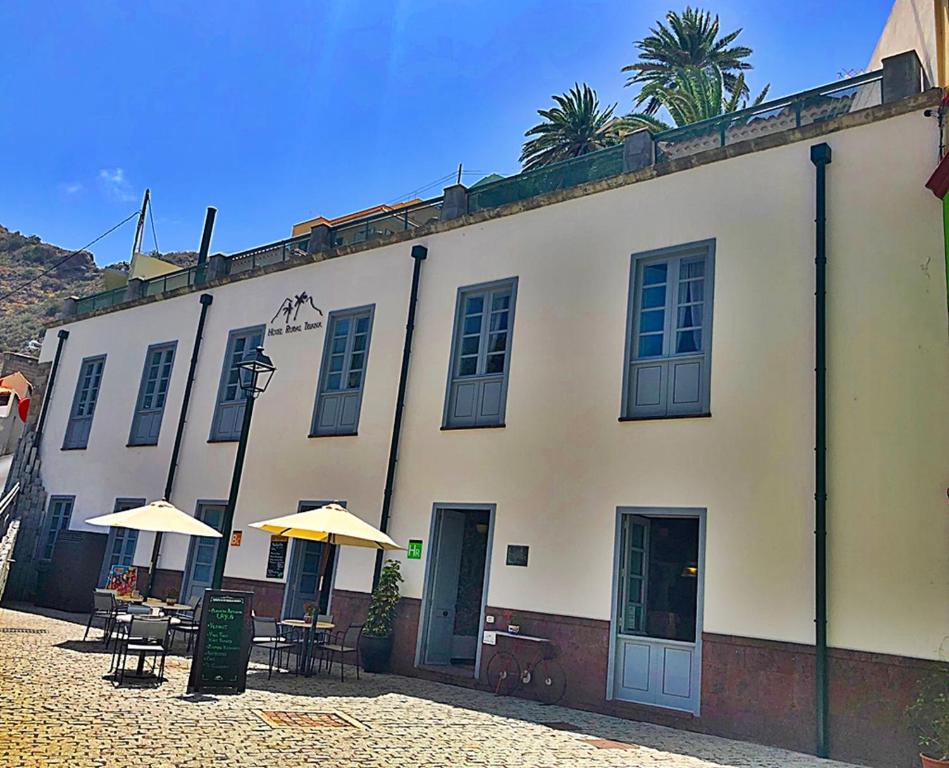 a building with tables and umbrellas in front of it at Hotel Rural Triana in Vallehermoso