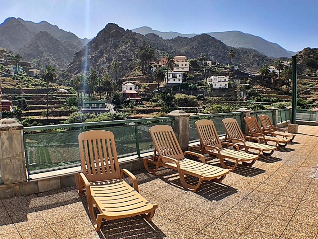 a row of chairs sitting on top of a balcony with mountains at Hotel Rural Triana in Vallehermoso